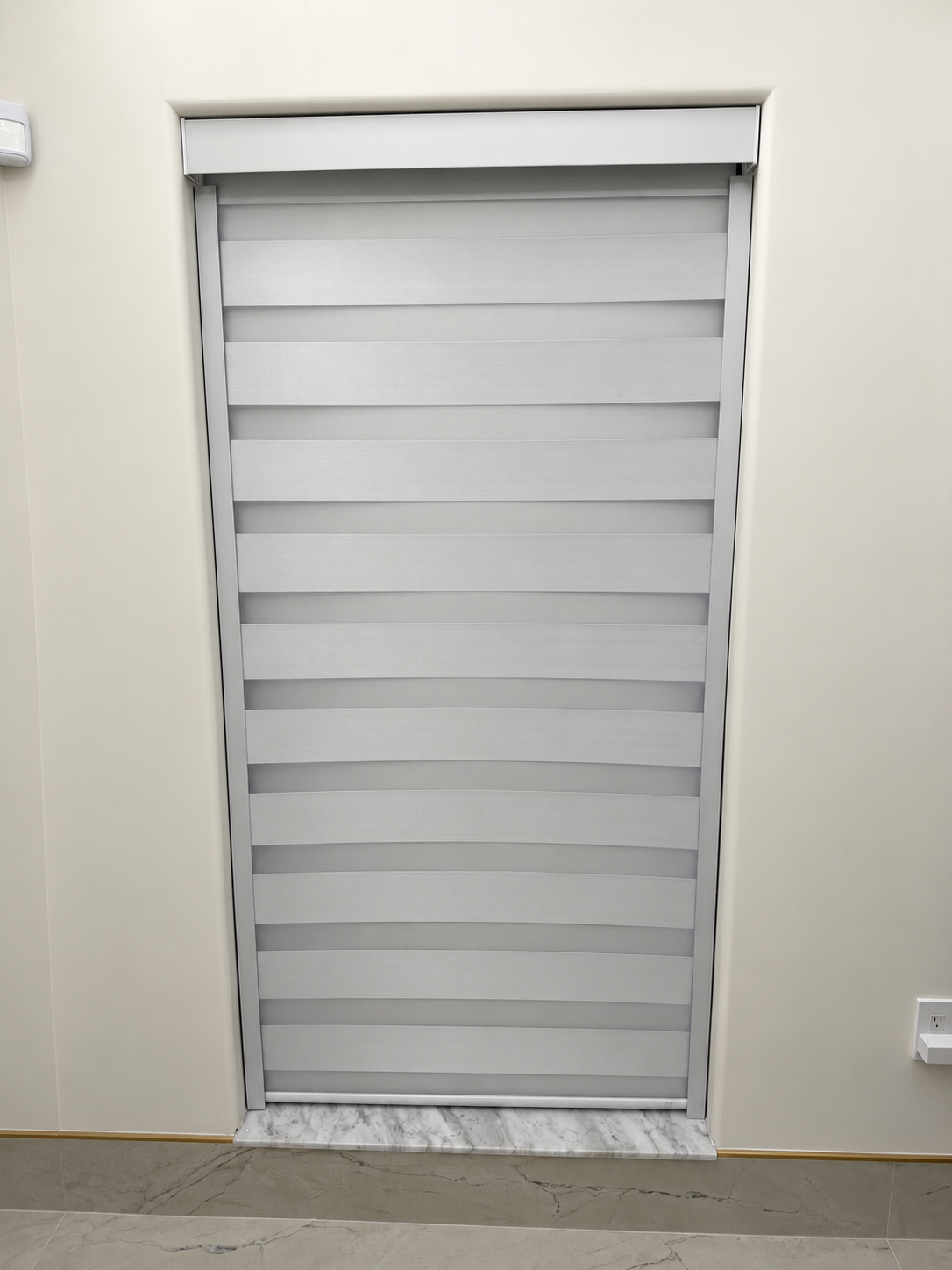 Motorized zebra blind within a tall window recess above a marble sill in a Fort Lauderdale house