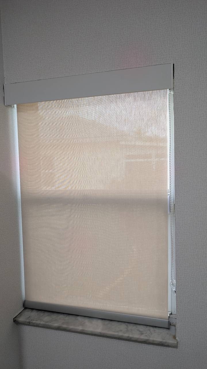 Roller sunscreen shade on a window beside a textured wall in Hollywood