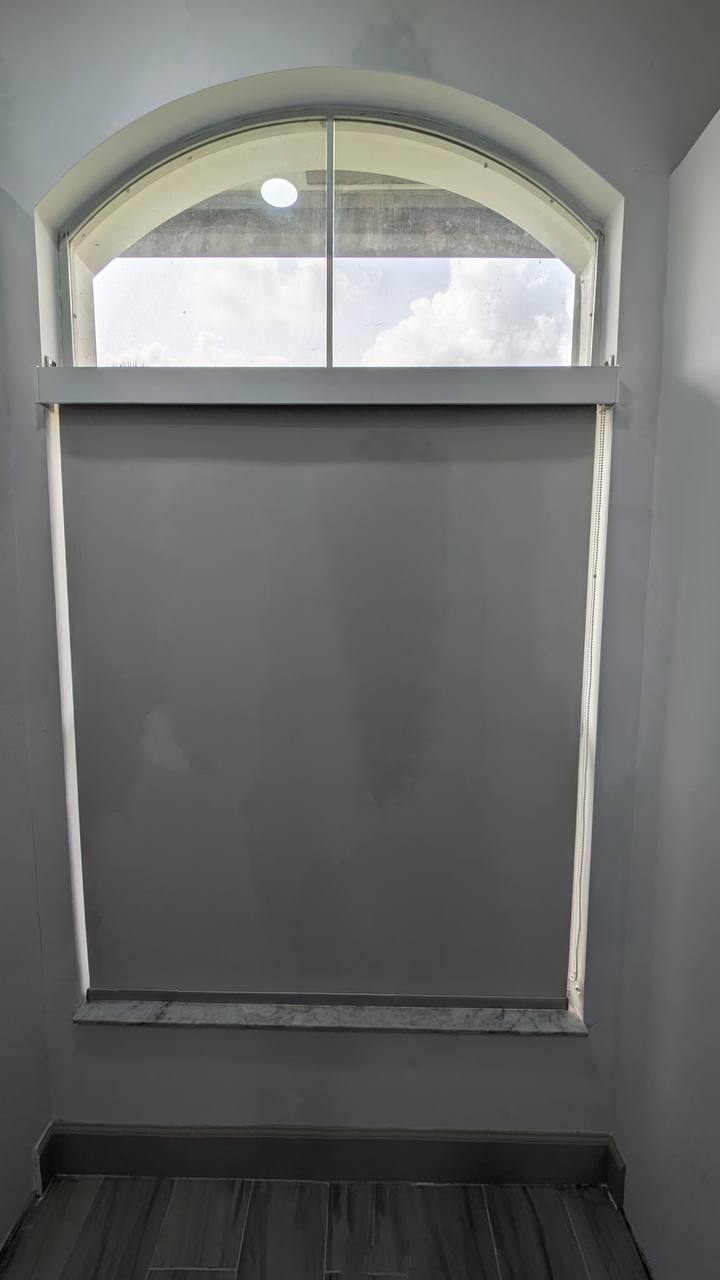 Roller shade installed below an arched window in a Hollywood FL house