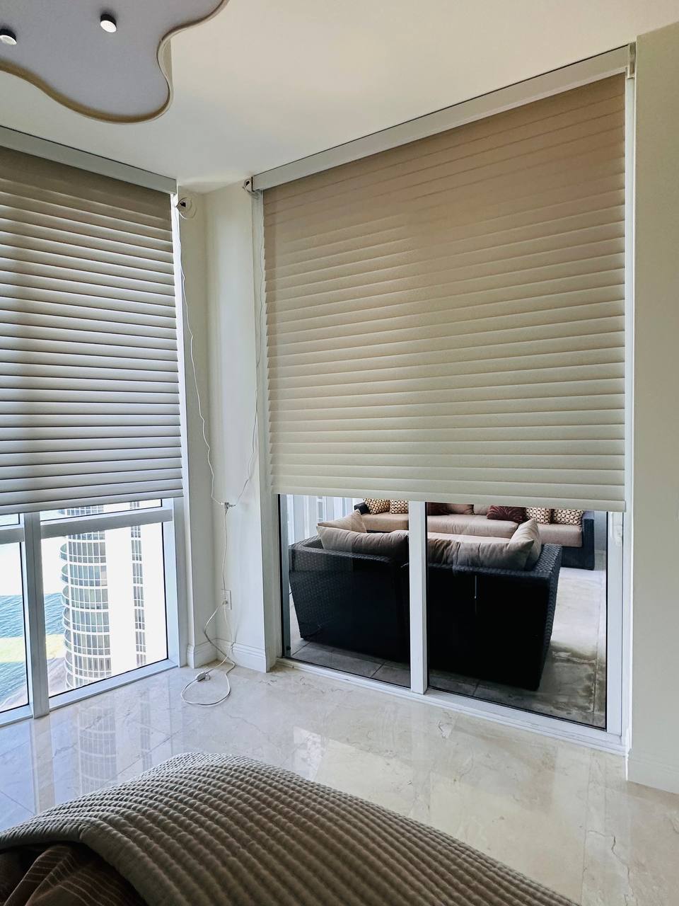 Motorized Shangri-La shades lowered over floor-to-ceiling glass and a sliding door in Miami