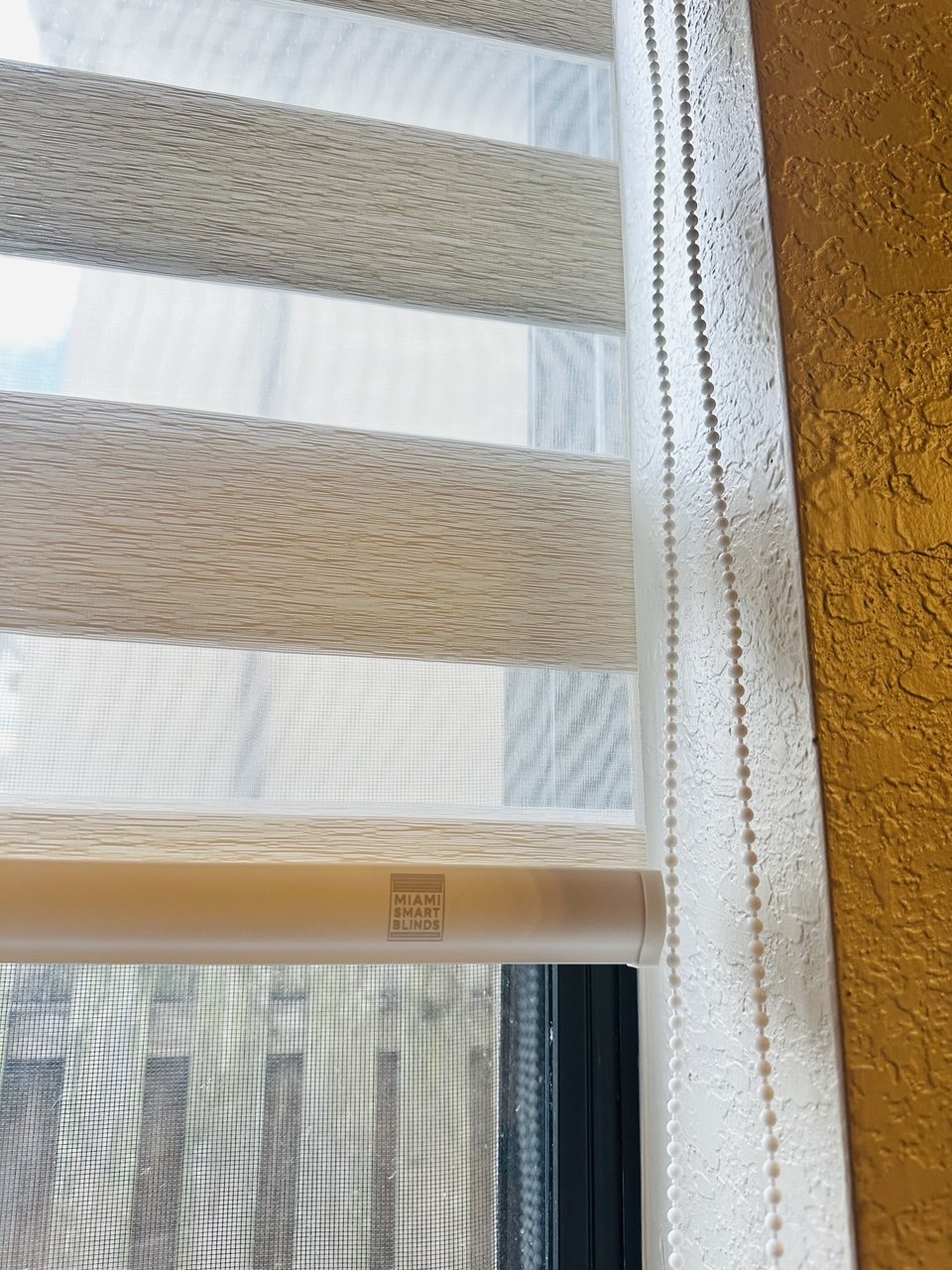 Close-up of a beige zebra shade with Miami Smart Blinds bottom bar