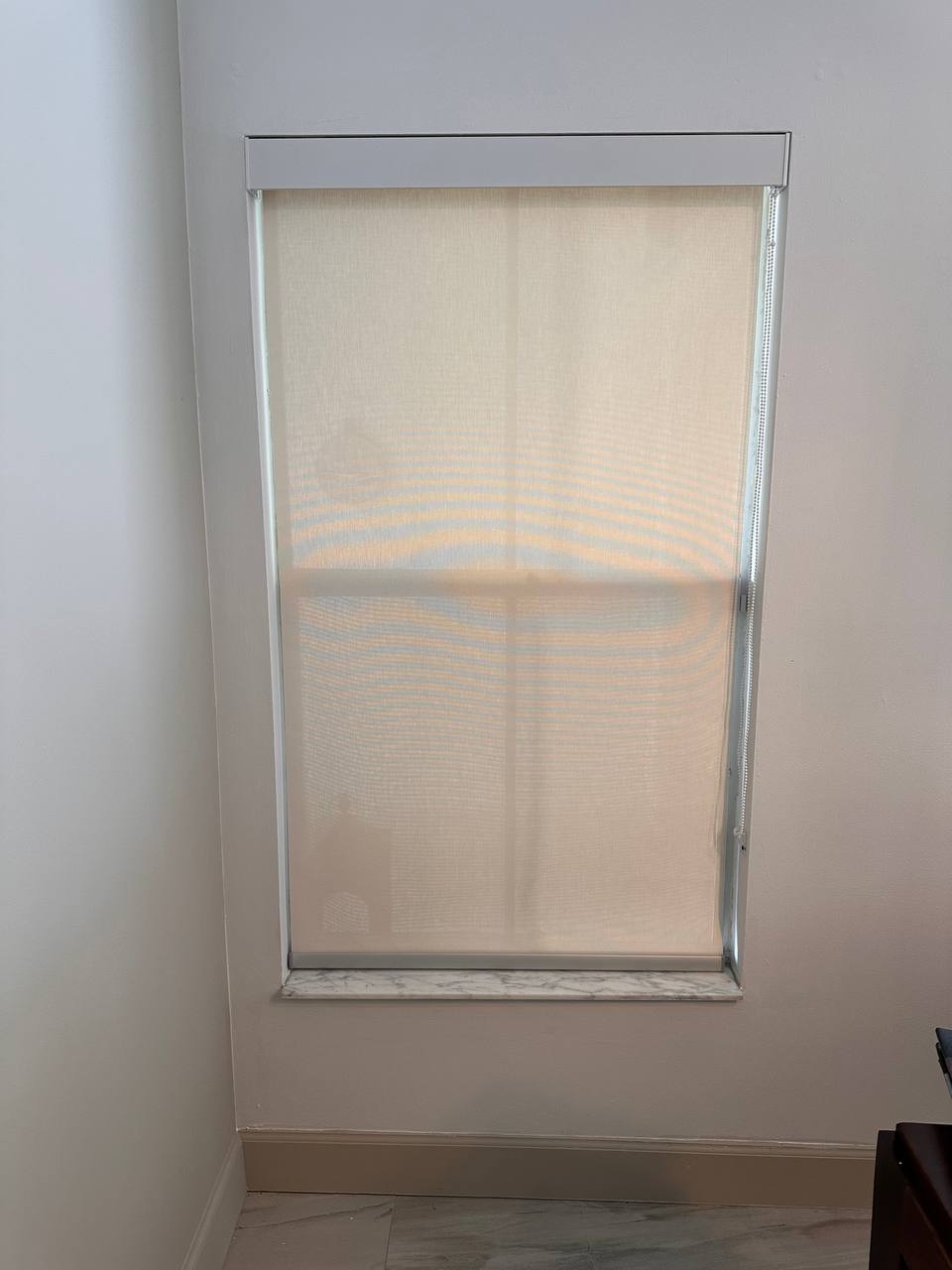Custom roller sunscreen shade on a double-hung window with marble sill in Hollywood