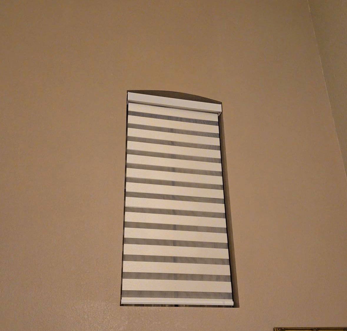 Motorized zebra shade fitted to a high arched window in Kendall