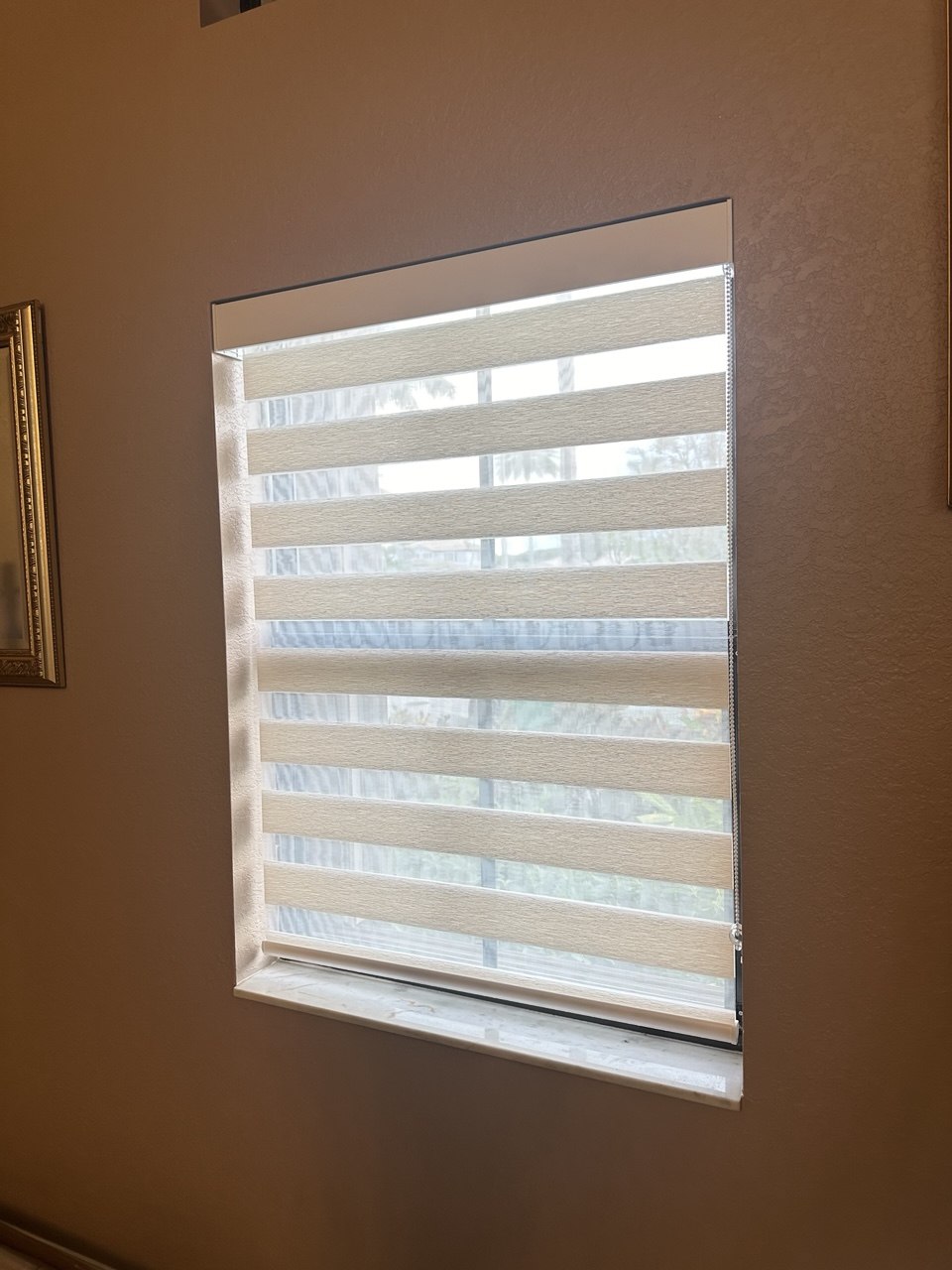 Beige zebra shade filtering daylight in a Kendall house