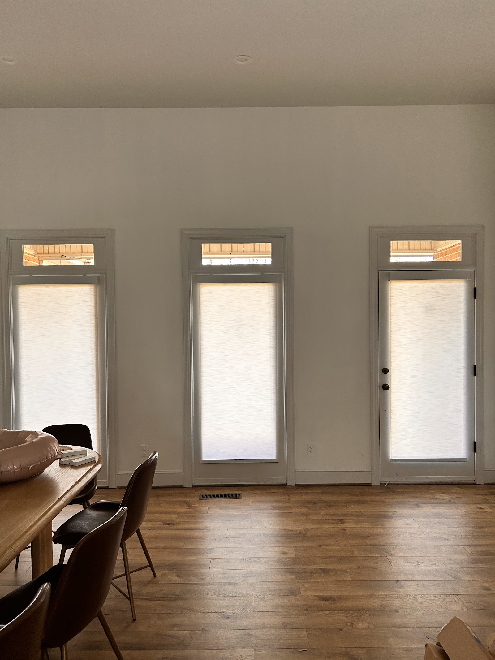 Light-filtering roller shades on tall patio doors and transom windows in a South Florida dining room