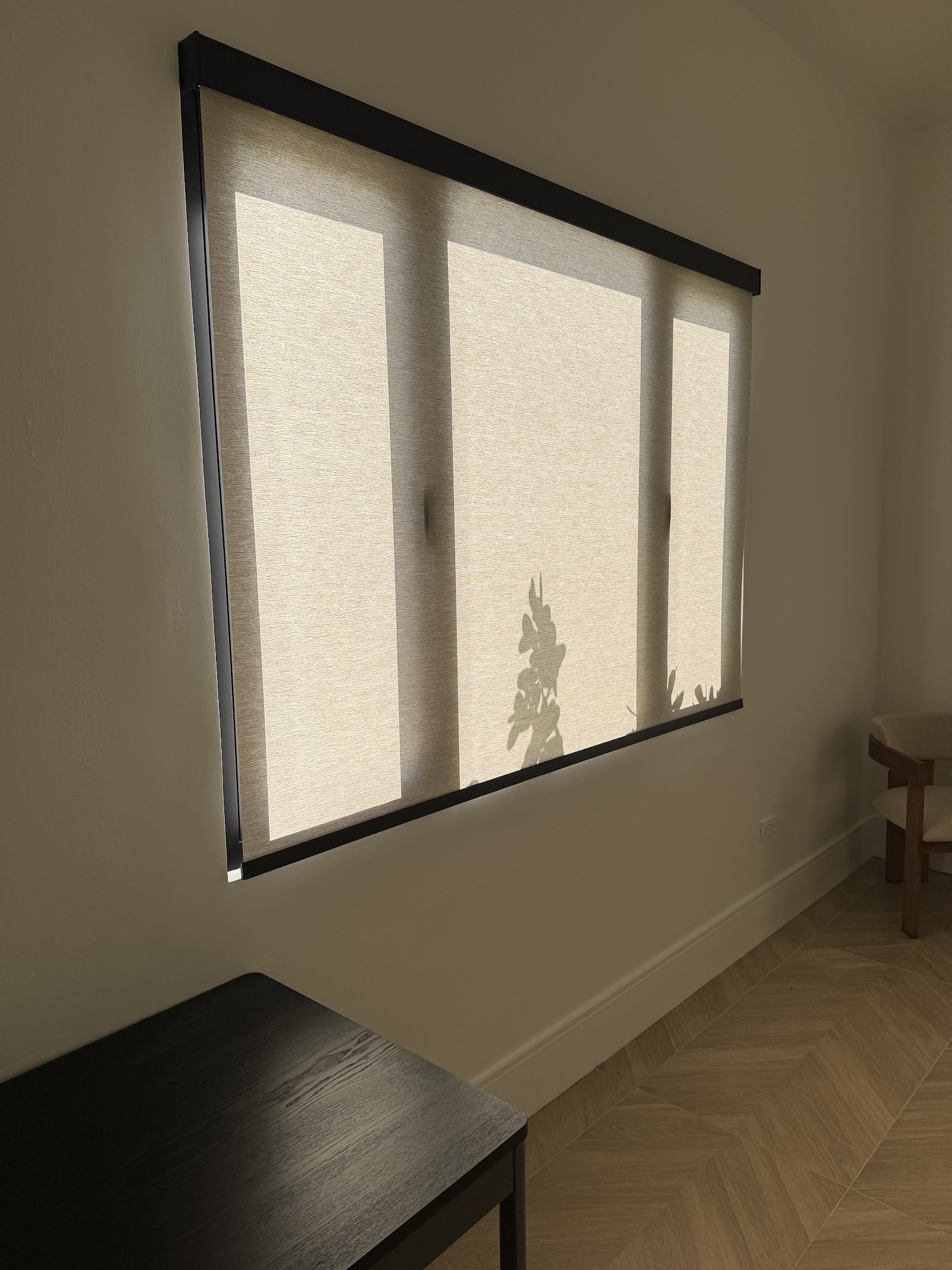 Textured roller shade with a black cassette on a wide living-room window